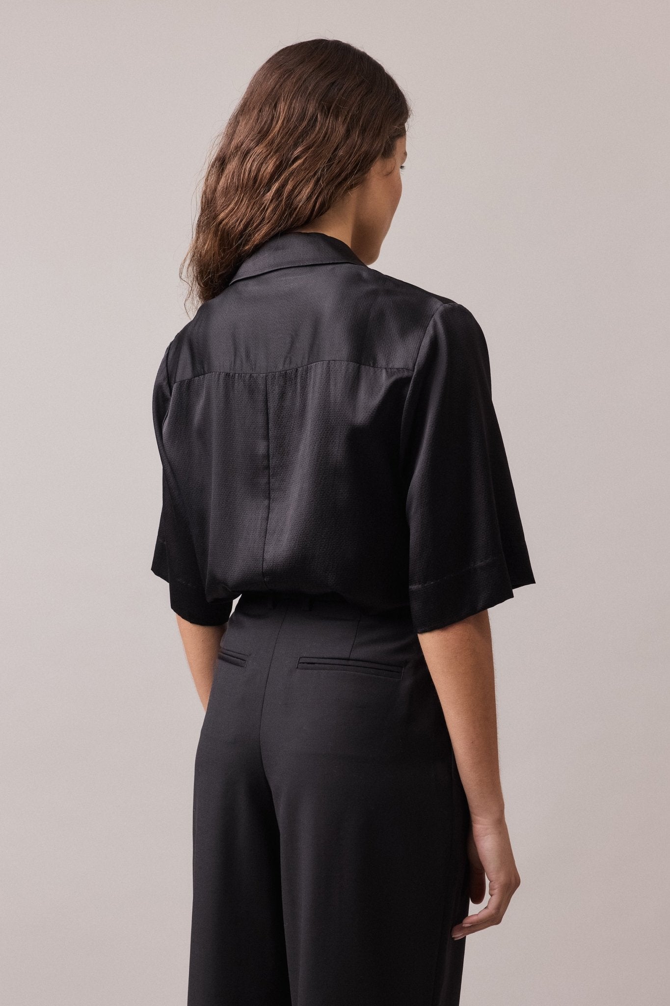 Close-up view of the back of the high-waist black Frankie Wide Leg Pant, highlighting the details of the back jet pockets.