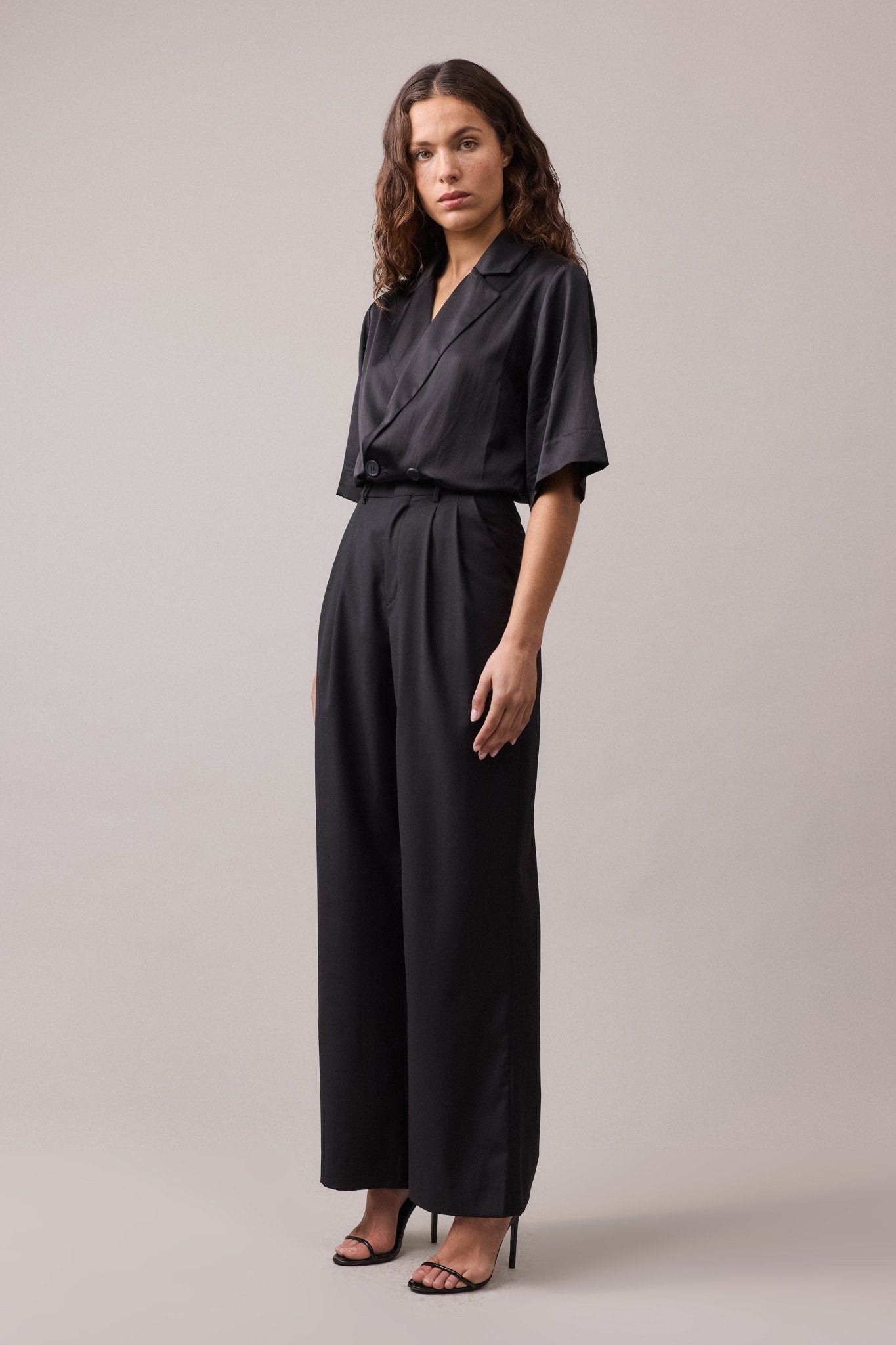 Woman wearing the black Frankie Wide Leg wool pant, paired with a black shirt. 