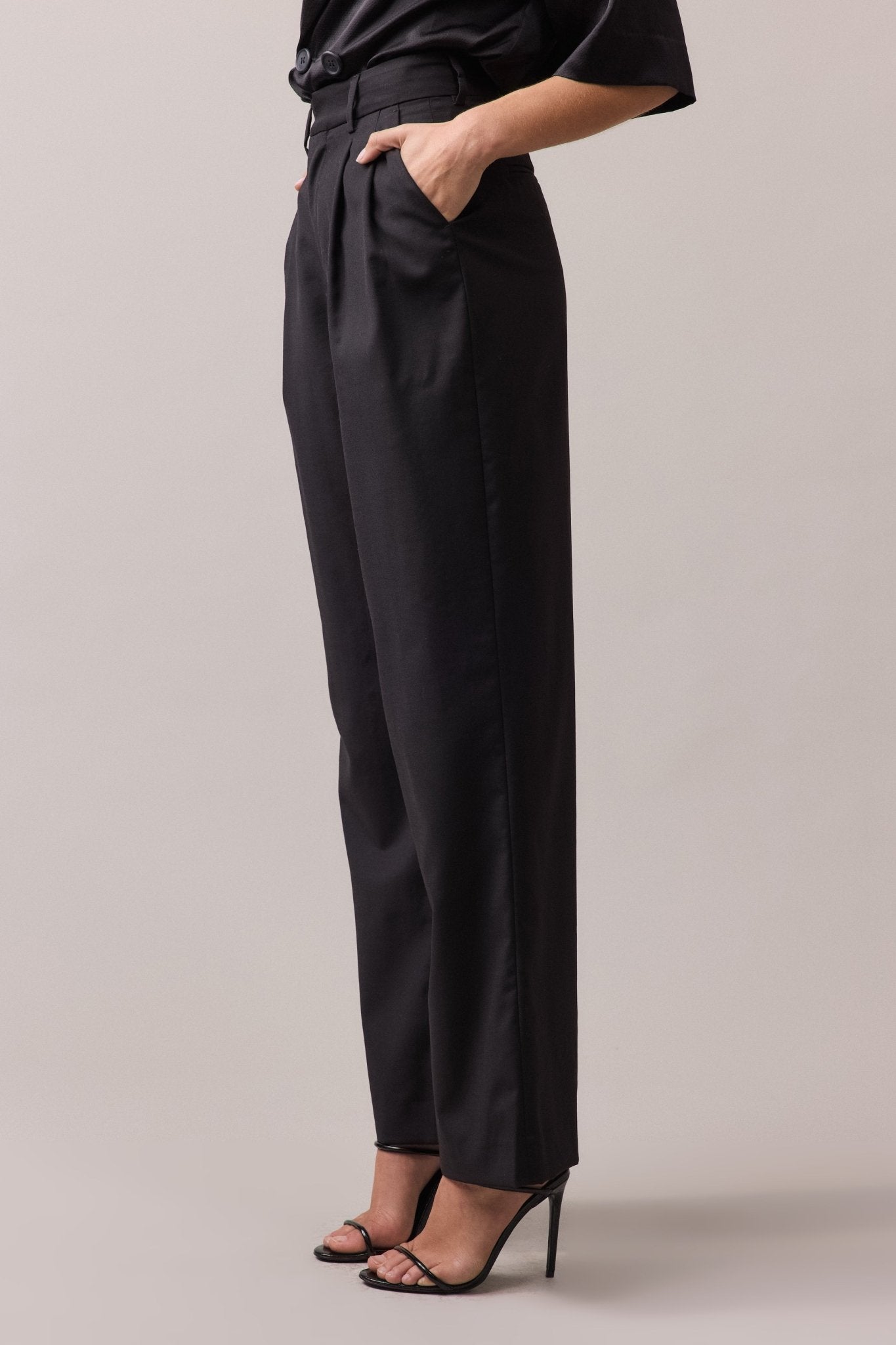 Side view of the woman wearing the black Frankie Wide Leg Pant, with her hands in the front side seam pockets.