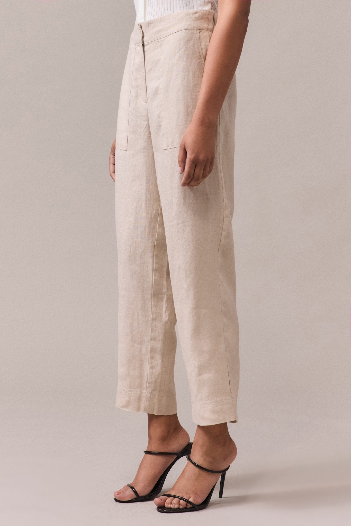 A woman wearing linen tapered pant with a slightly cropped length, tailored front waist.