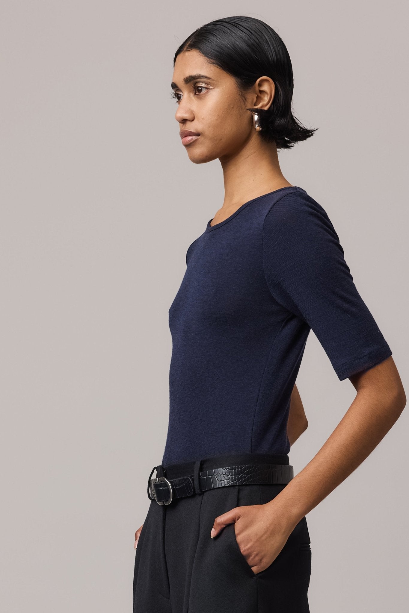 Side close-up of a woman wearing an indigo Merino Wool Crew Neck Tee.