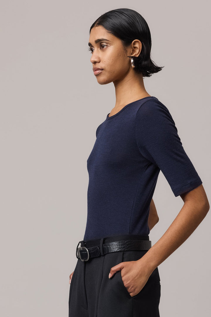 Side close-up of a woman wearing an indigo Merino Wool Crew Neck Tee.