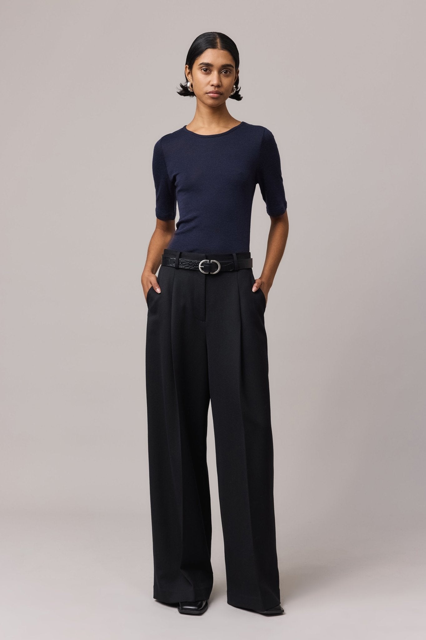 Woman wearing an indigo Merino Wool Crew Neck Tee with elbow sleeves and black linen pants.