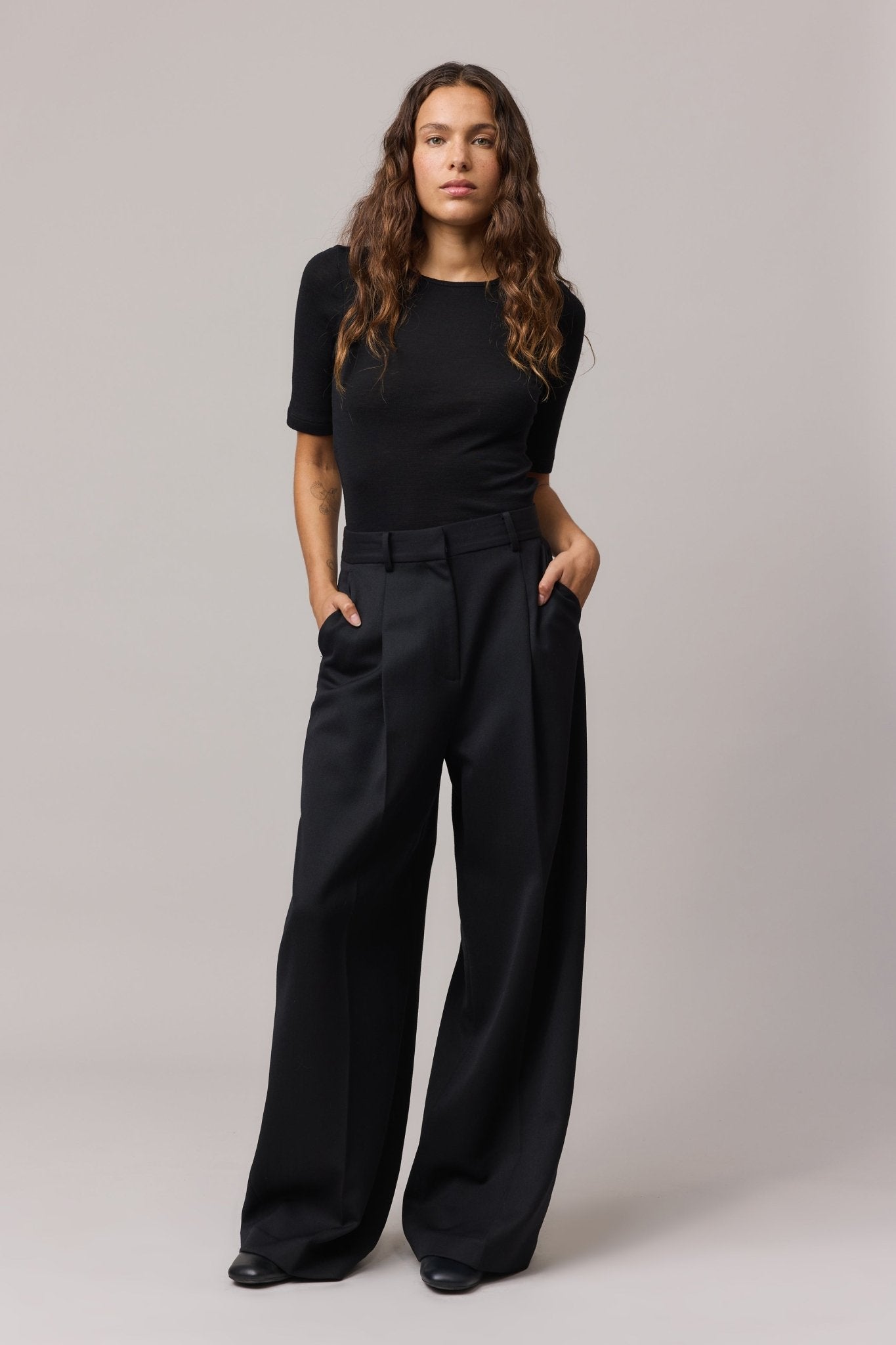 Woman wearing a black Merino Wool Crew Neck Tee with elbow sleeves and black linen pants.