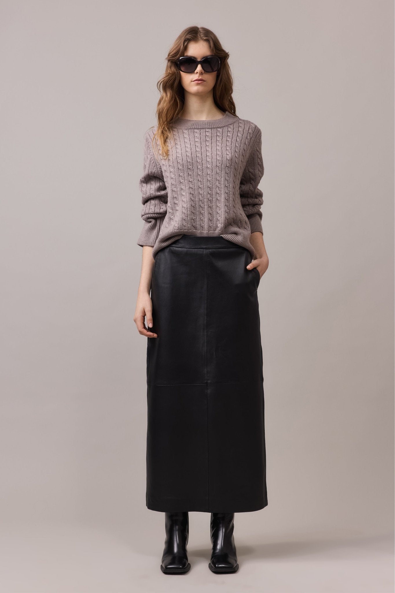 Woman is wearing merino wool cable knit with long black leather skirt.