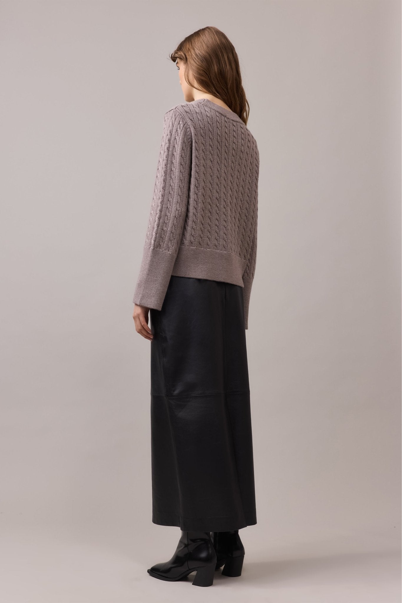 Woman, seen from the back, is wearing merino wool knit with black maxi skirt.