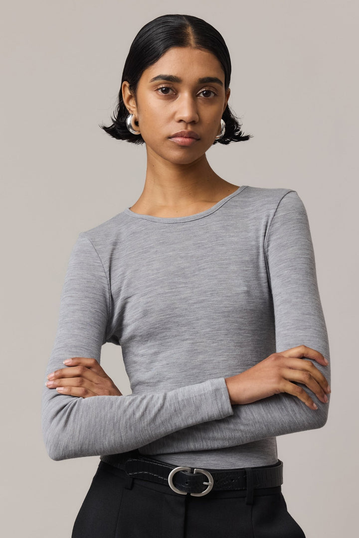 Close-up of a woman wearing a long-sleeve Merino Wool Crew Neck with crossed arms, paired with black linen pants.