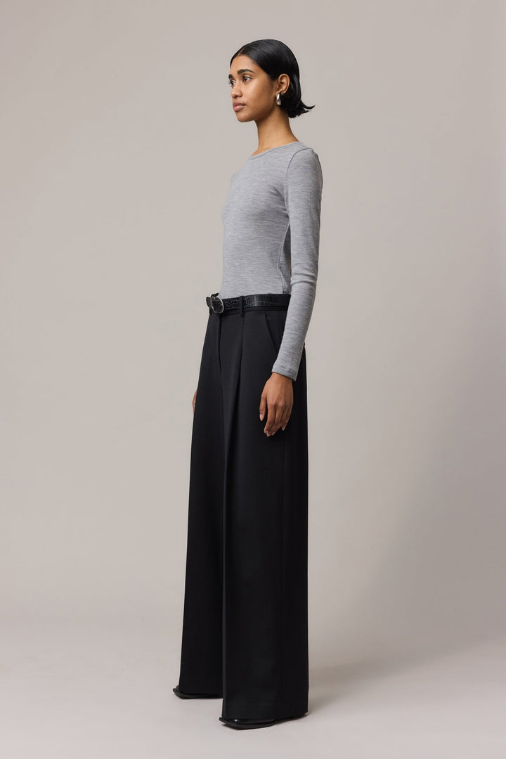 Side view of a woman wearing a long-sleeve Merino Wool Crew Neck with black linen pants.