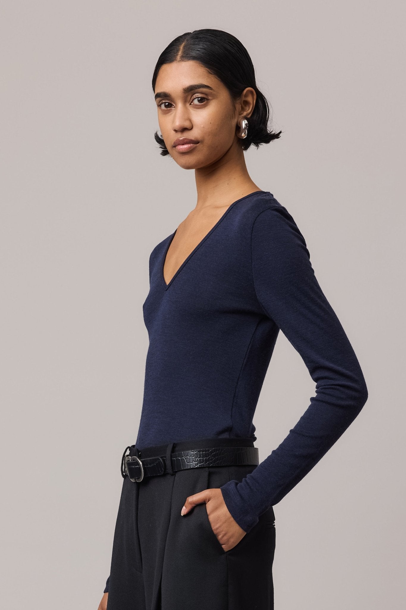 Side view close-up of the indigo Merino Wool V Neck Top, focusing on its sleek silhouette and fine Merino wool fabric.