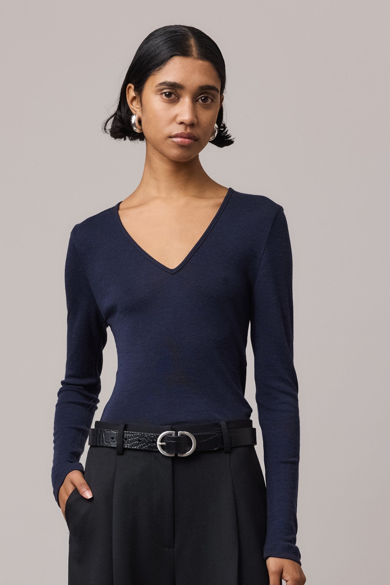 Close-up of a woman wearing an indigo Merino Wool V Neck Top, showcasing its soft fabric.