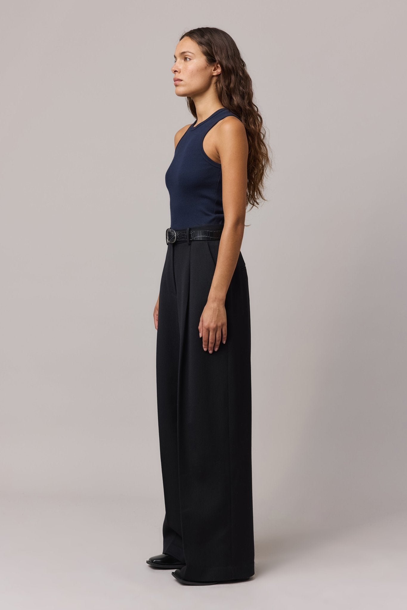 Side view of the woman in the indigo cotton rib tank top, showing the fitted shape.