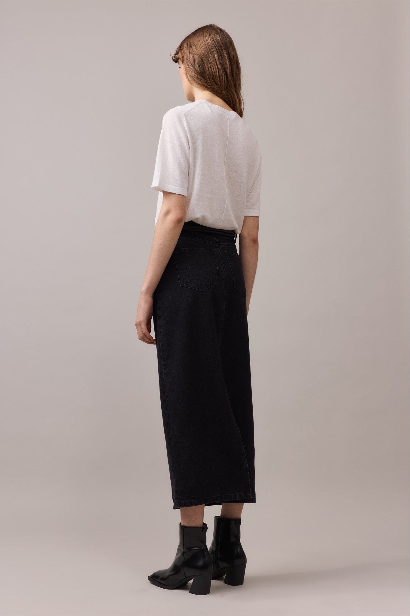 Back view of the woman, highlighting the silhouette of the maxi denim skirt.