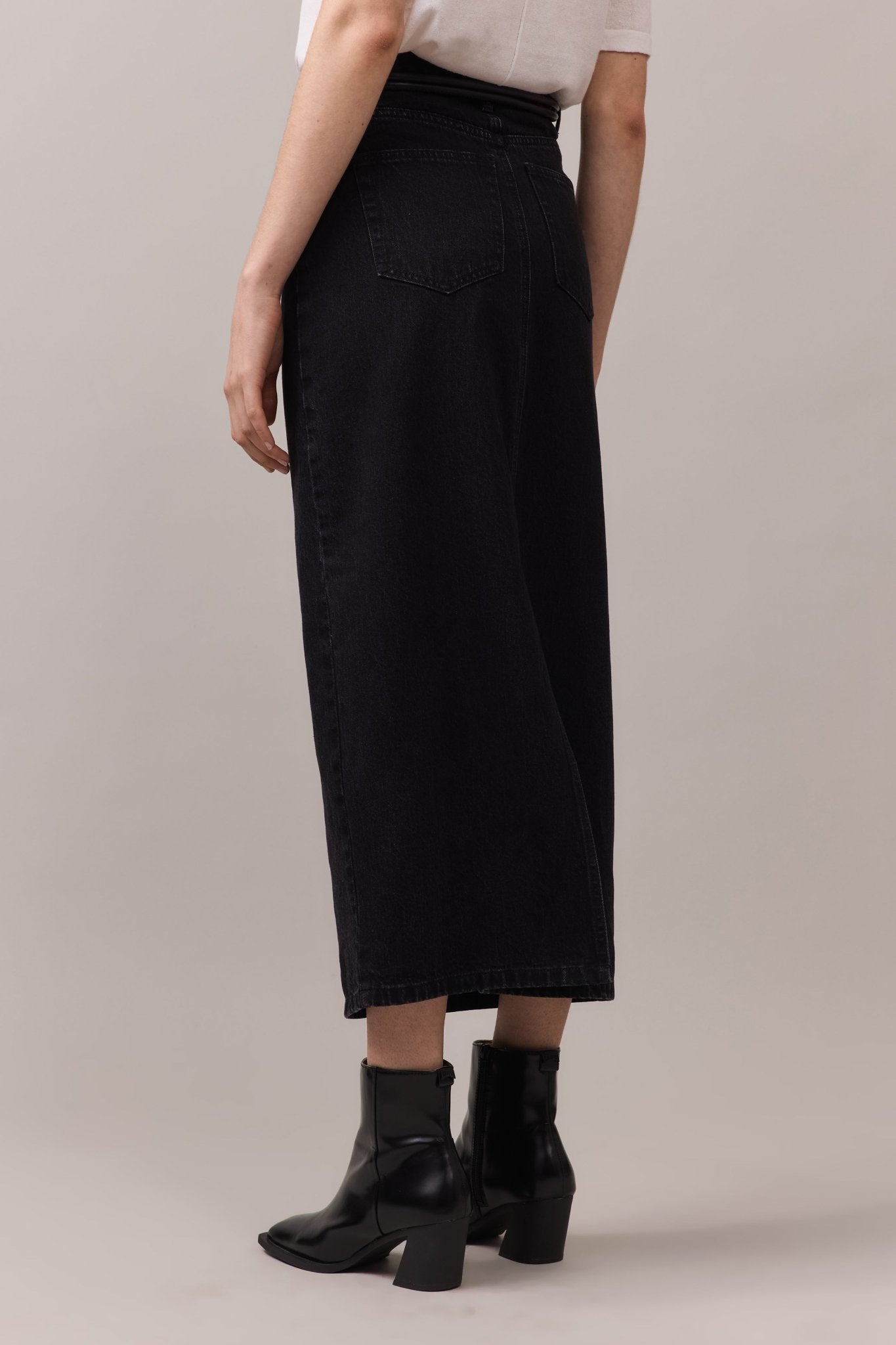 Side view of the maxi denim skirt, highlighting its soft, washed black fabric and the flattering longline cut.