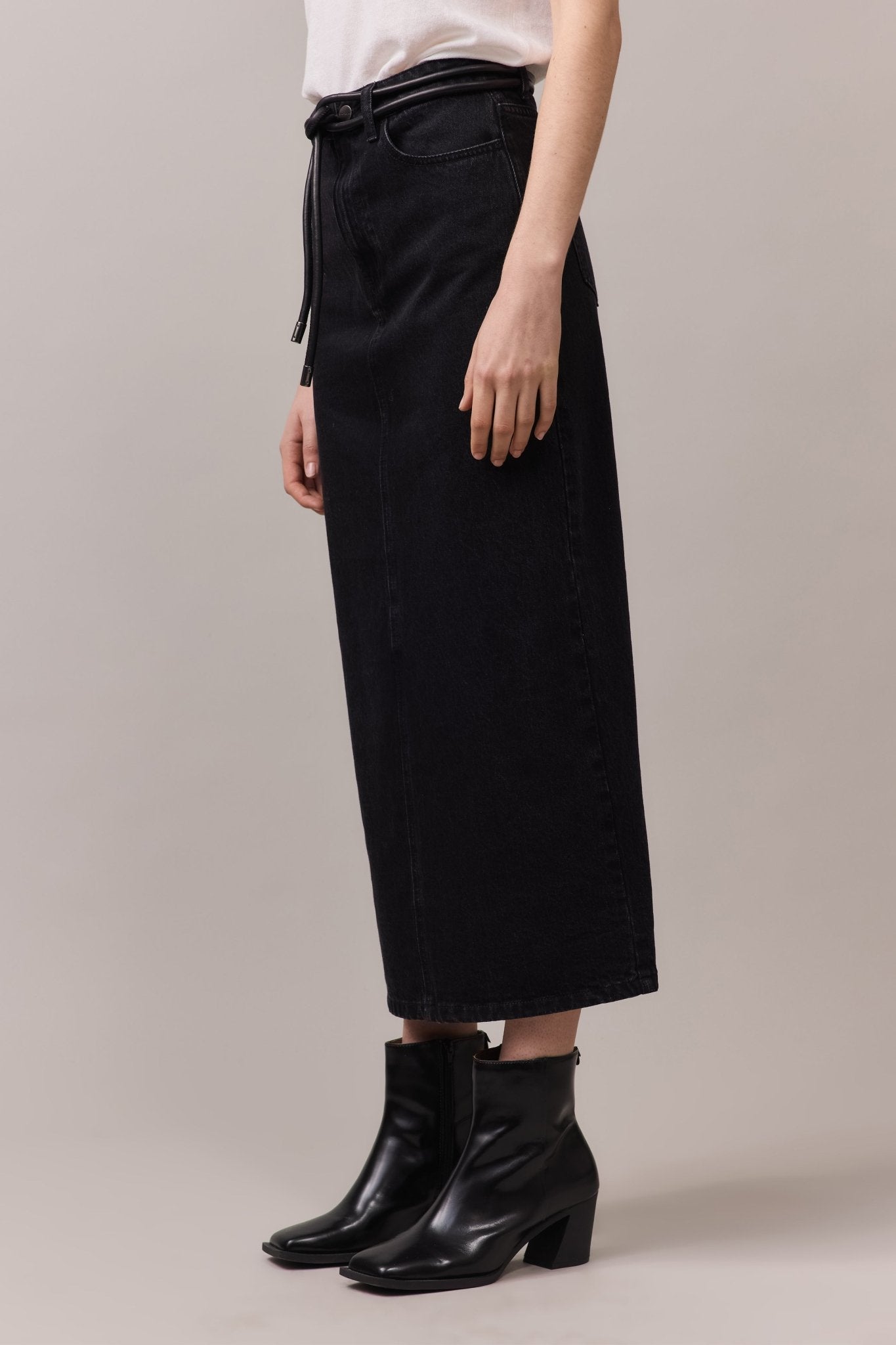 Close-up side view of the maxi denim skirt, emphasizing the soft, washed black cotton fabric and the longline cut that skims the ankles.