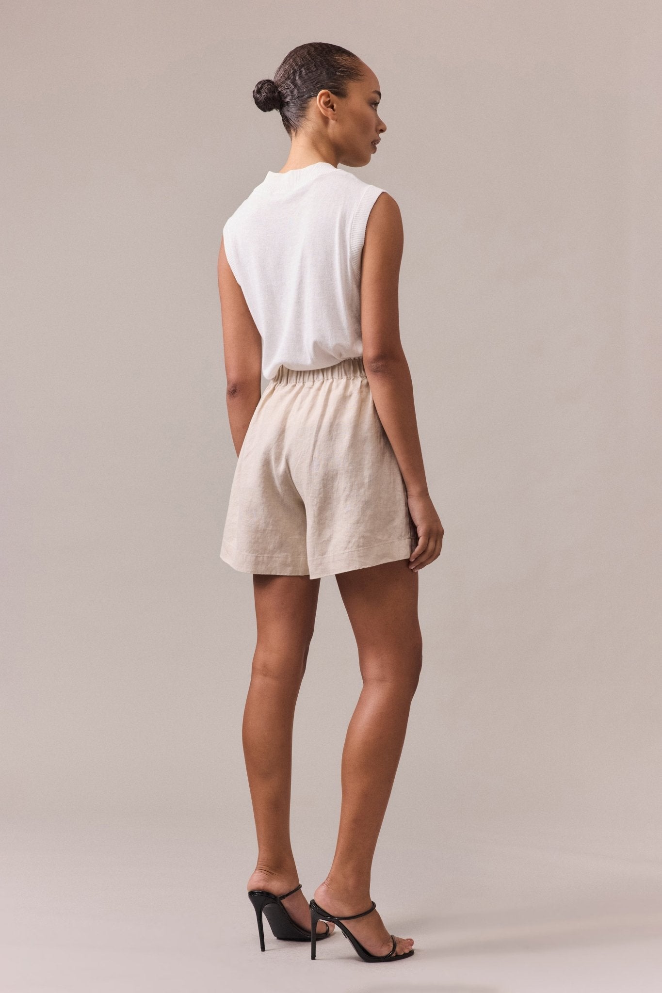 Back view of the sand Soma linen shorts, showing the elasticated waistband and how the fabric drapes naturally. 