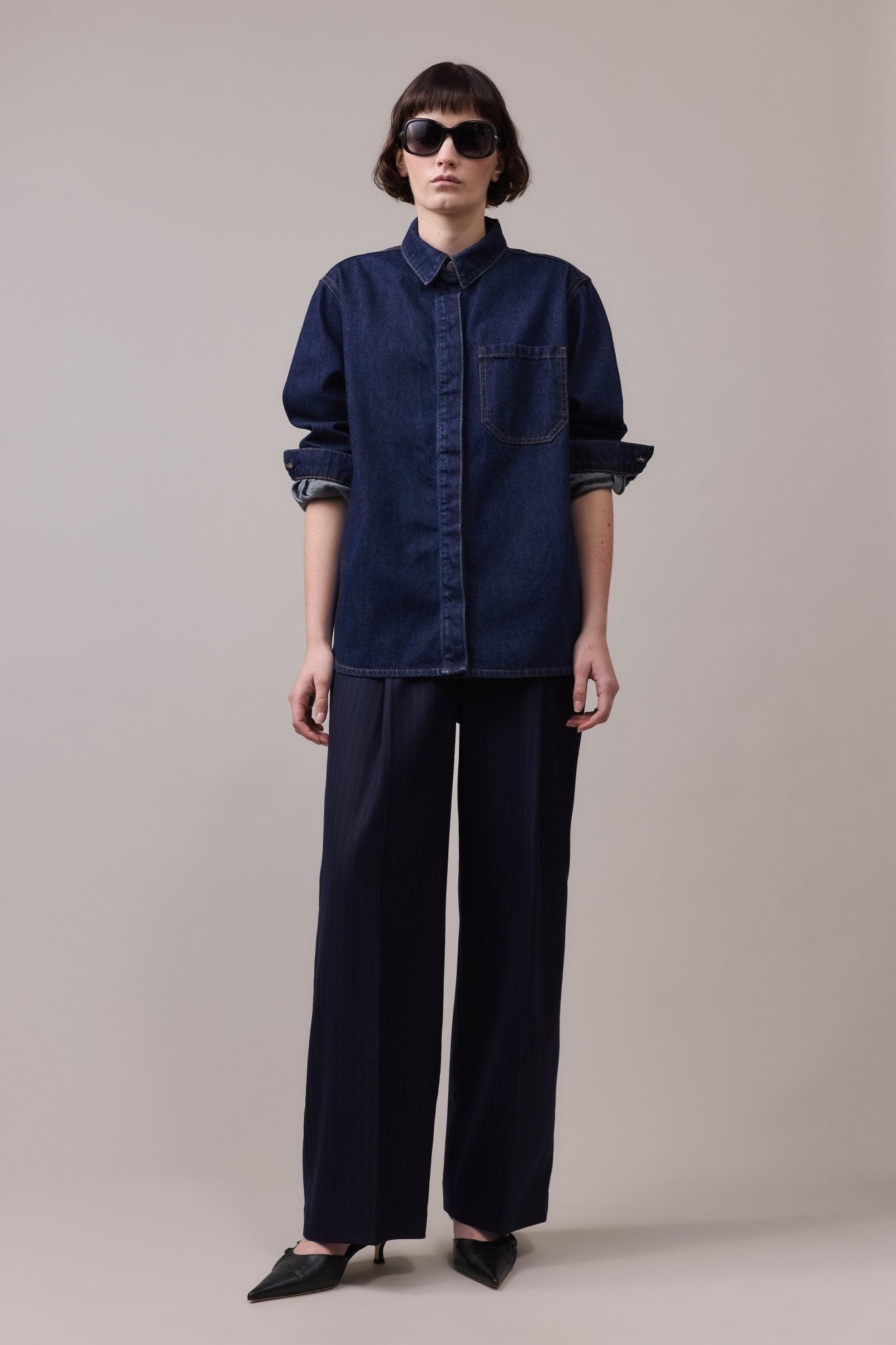 Woman is wearing vintage cotton denim shirt at the top. On the bottoms she's wearing wide leg blu pants.